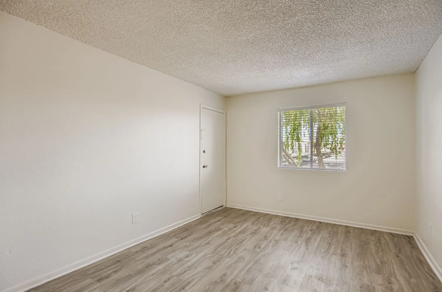 Bedroom with entry door, window, wood-style plank flooring