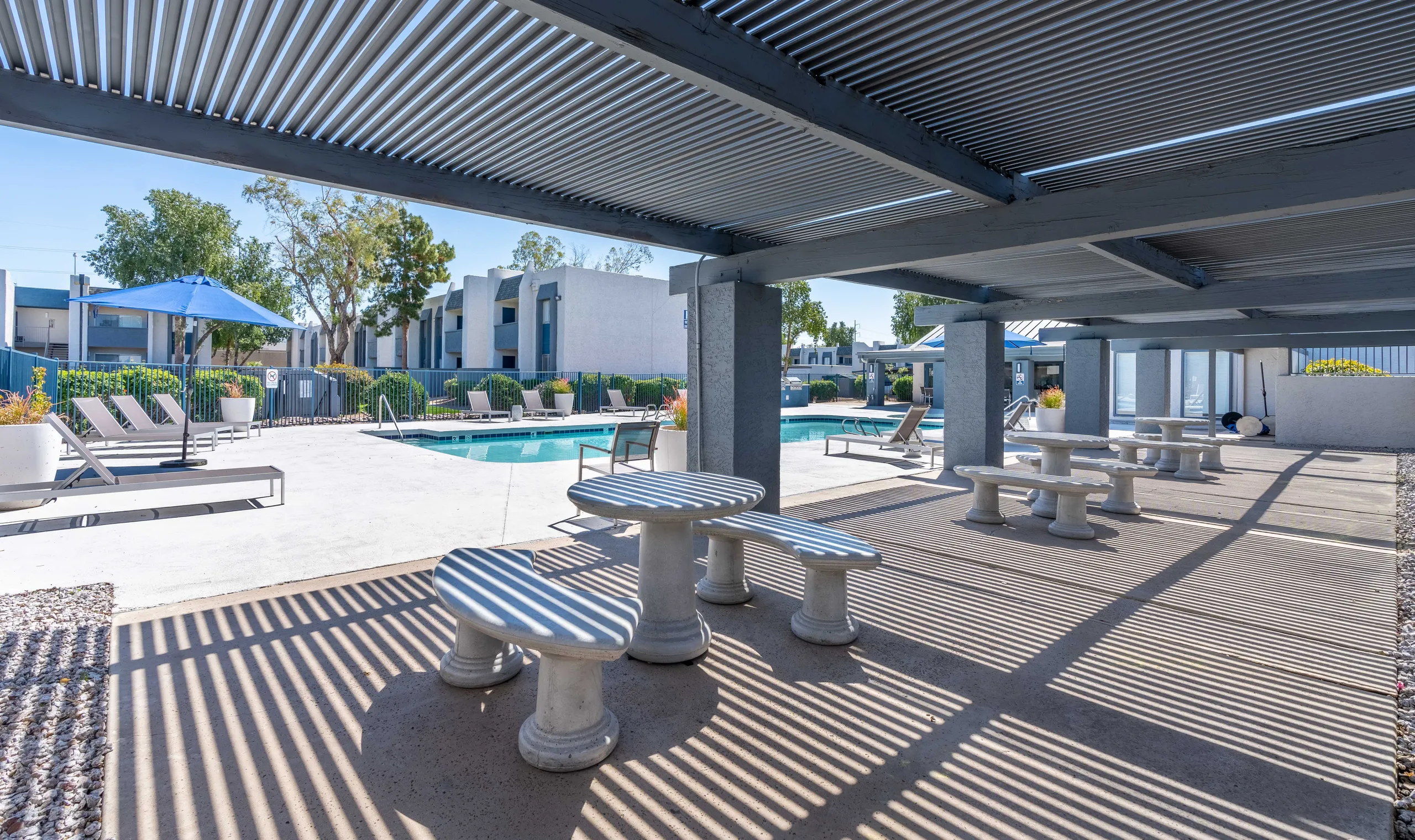Covered patio seating, poolside tables, shaded lounge area