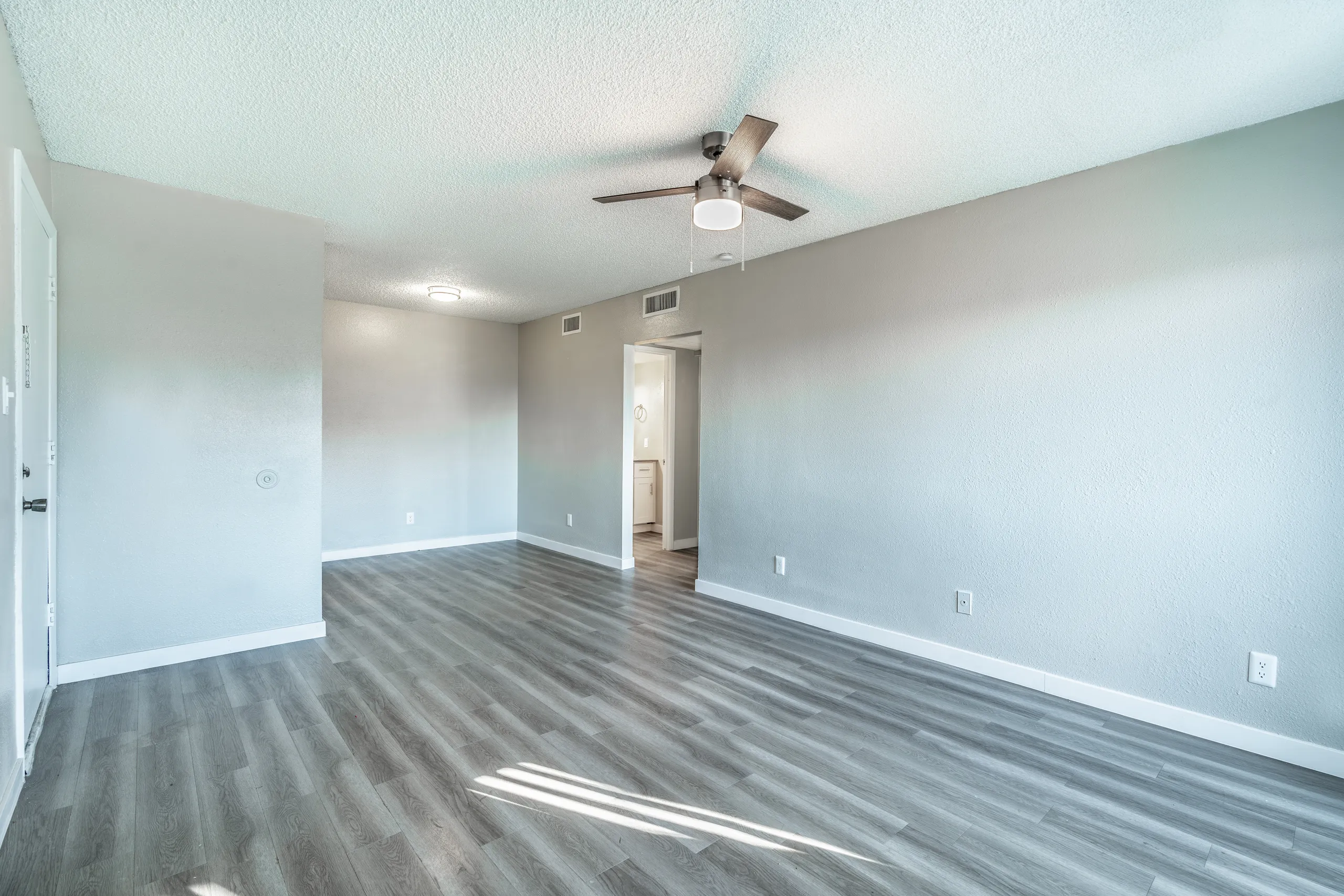 A2 Platinum living room, ceiling fan, bathroom entry visible, wood-style plank flooring