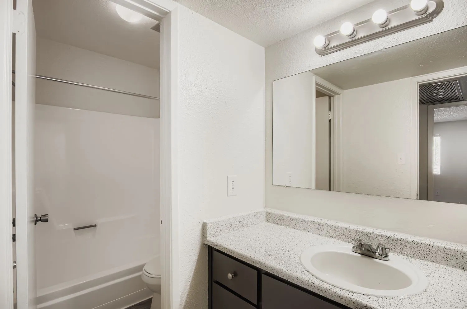 Vanity with speckled counter, framed mirror, tub/shower combo