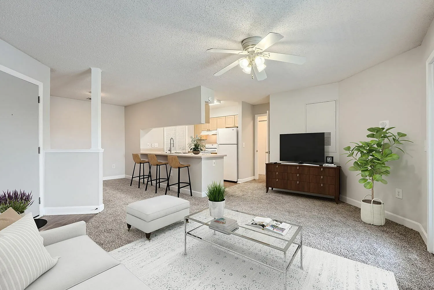 A2 Classic floor plan, living room with wood-style plank flooring, ceiling fan, staged furniture, view into kitchen with breakfast bar