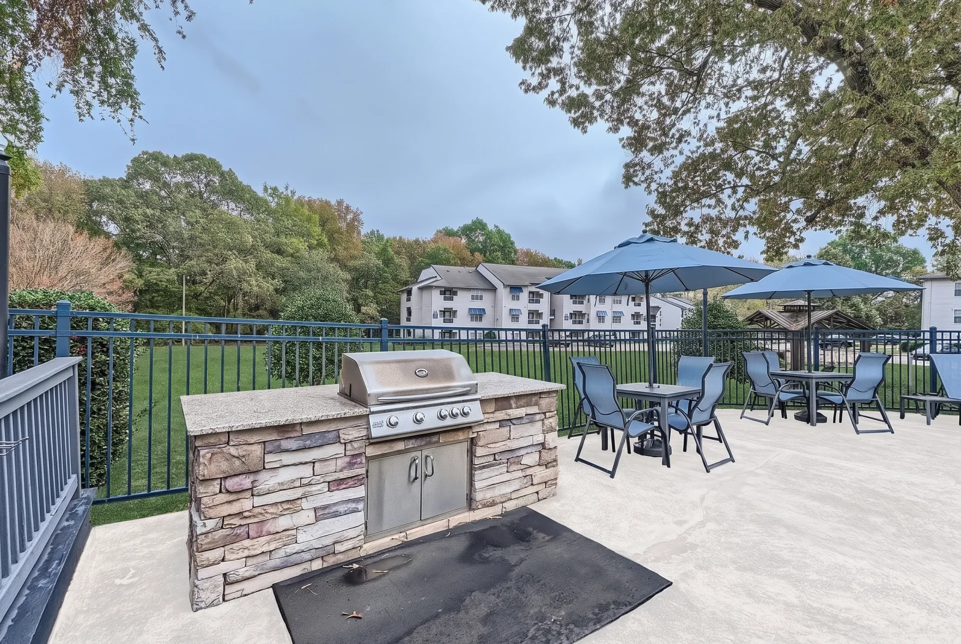 Outdoor BBQ grill station with stone counter and patio seating