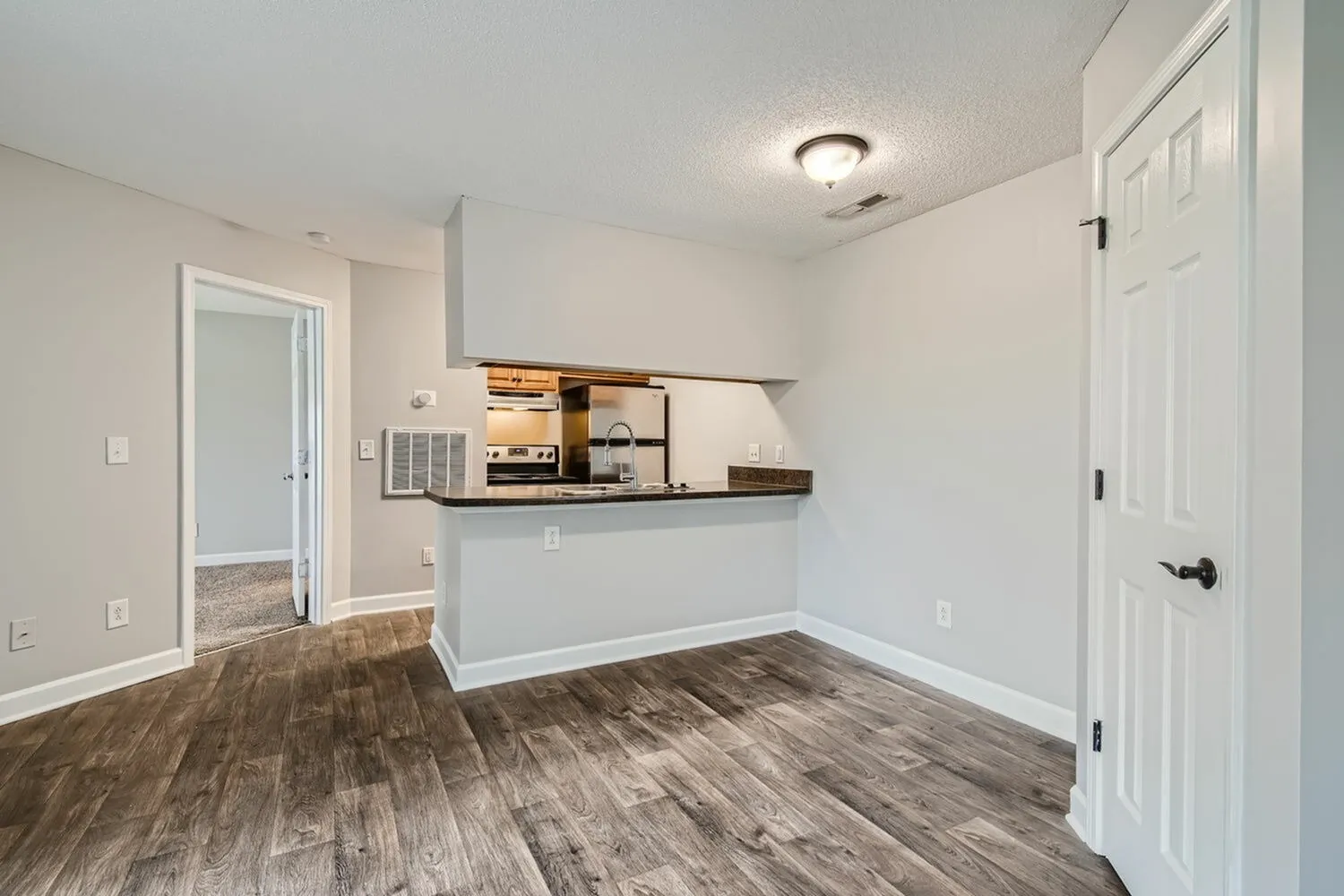 Kitchen with wood cabinetry, laminate countertops, pass-through view to living room