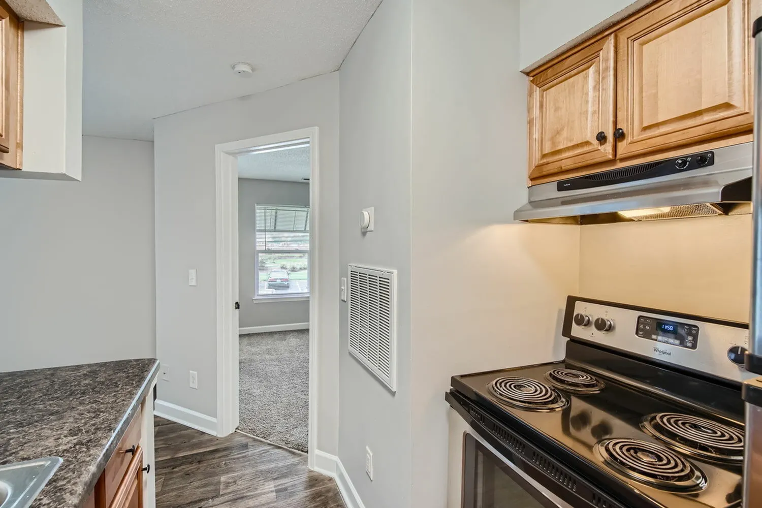 Kitchen with wood cabinetry, electric range, view into hallway