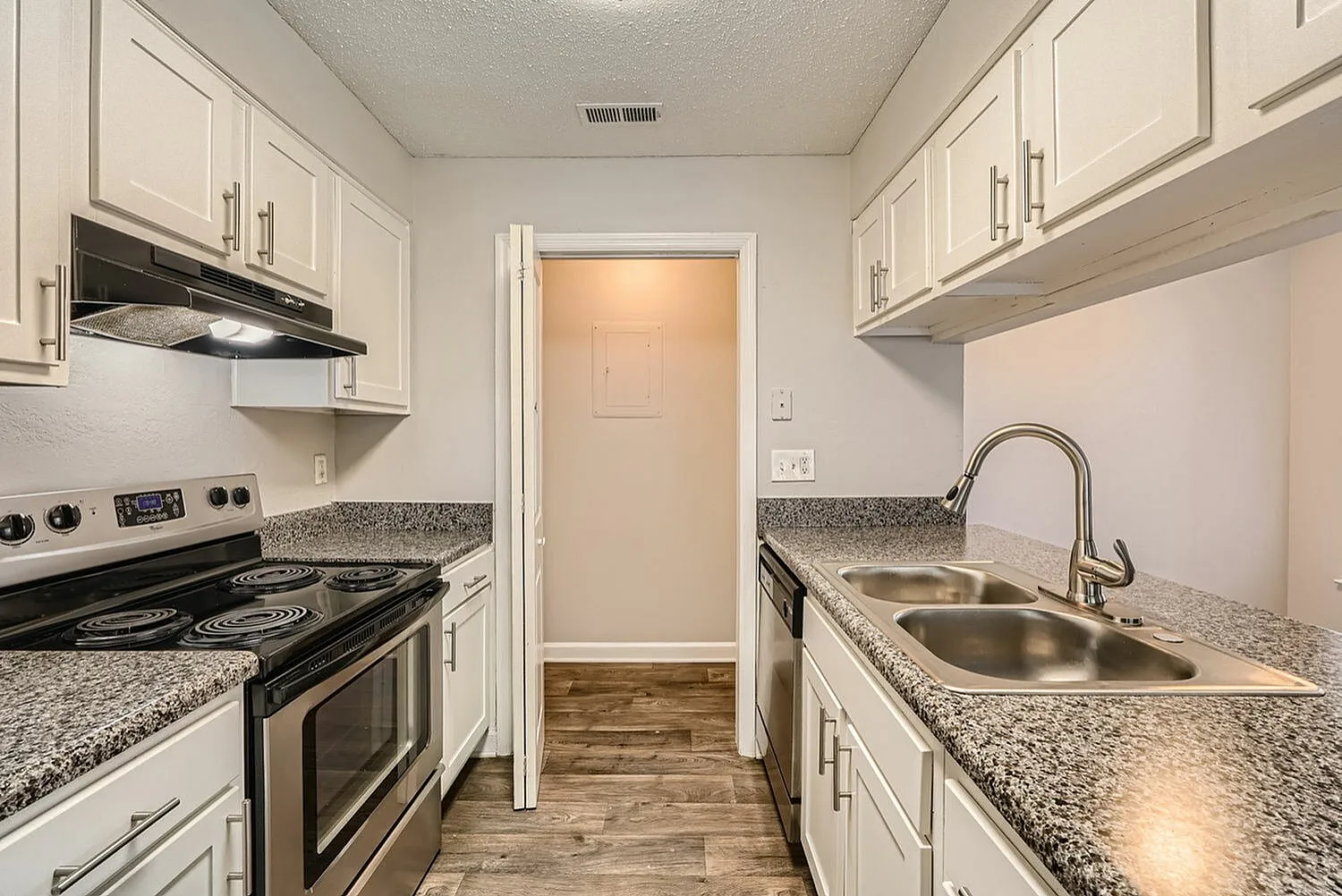 Kitchen with white cabinetry, countertops, pantry closet, view into hallway