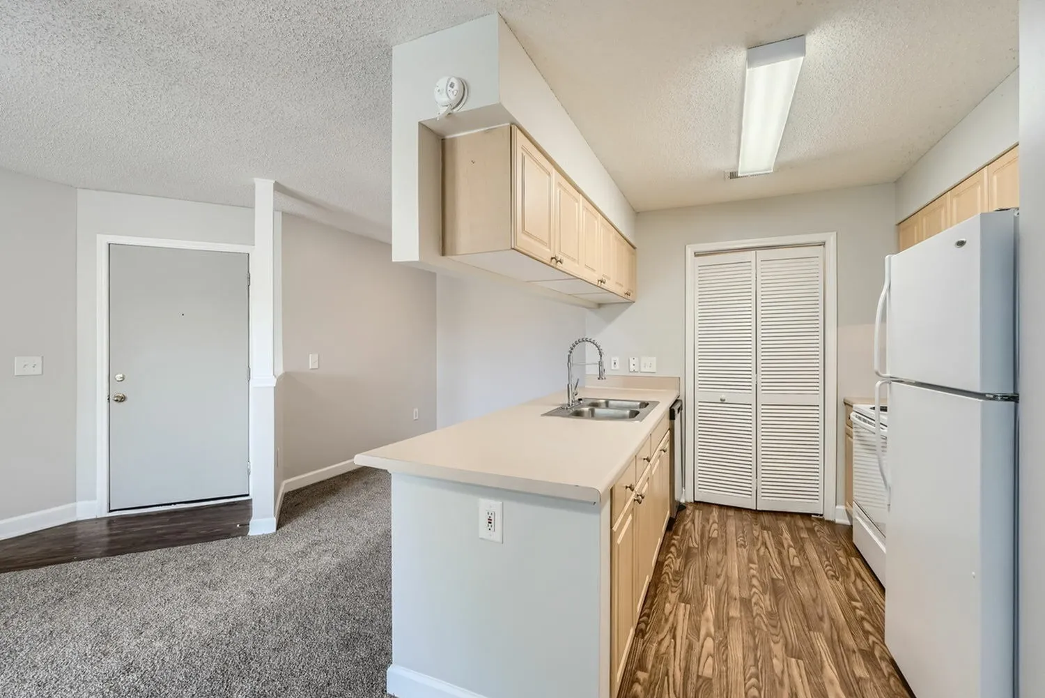 Kitchen with cabinetry, laminate countertops, view into hallway