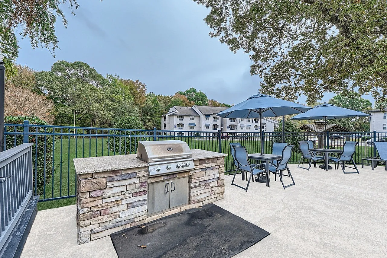 Outdoor BBQ grill station with stone counter and patio seating