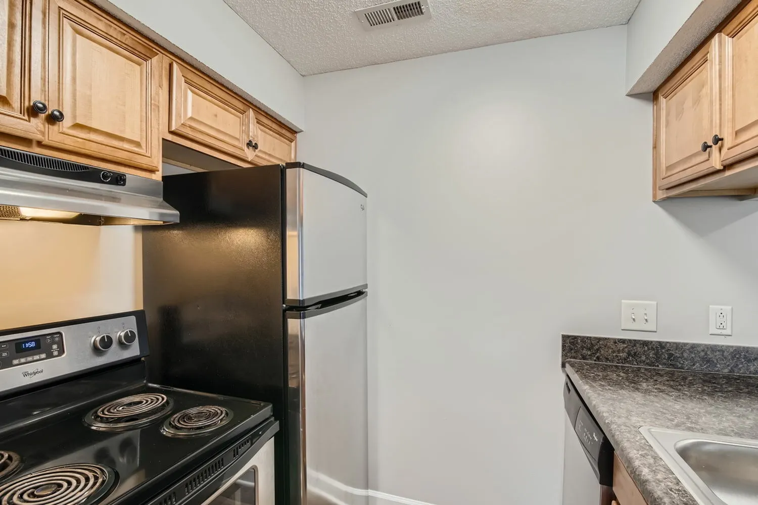 Kitchen with wood cabinetry, laminate countertops, electric range, refrigerator