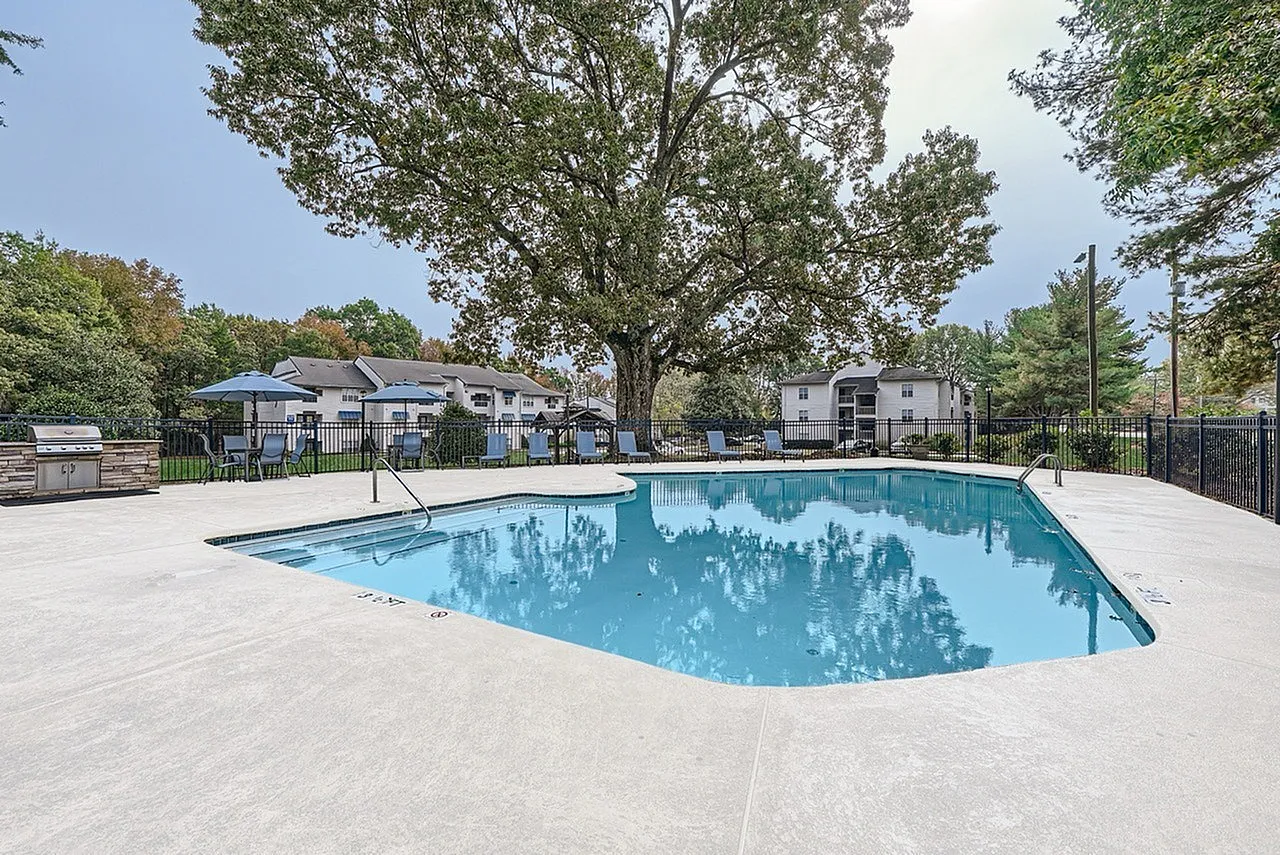 Community pool with surrounding lawn and mature trees