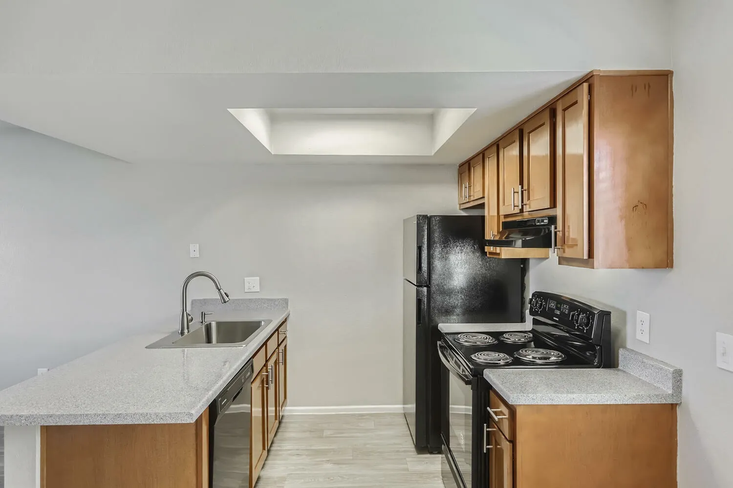 Kitchen, wood cabinetry, quartz countertops, black appliances, wood-style plank flooring