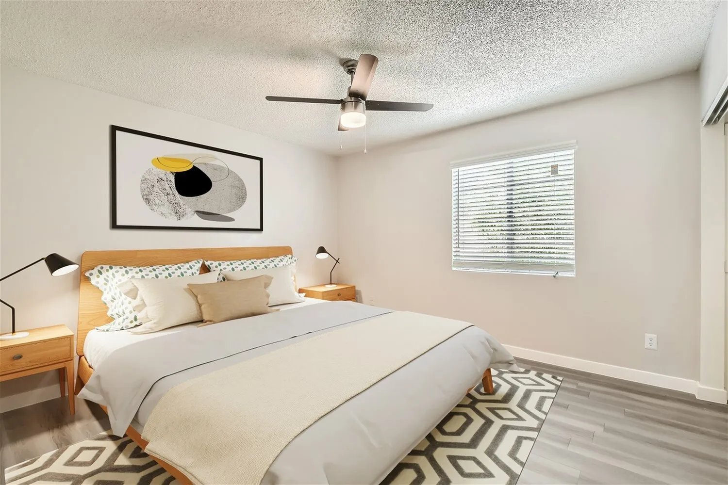 Primary bedroom, wood-style plank flooring, ceiling fan, framed artwork