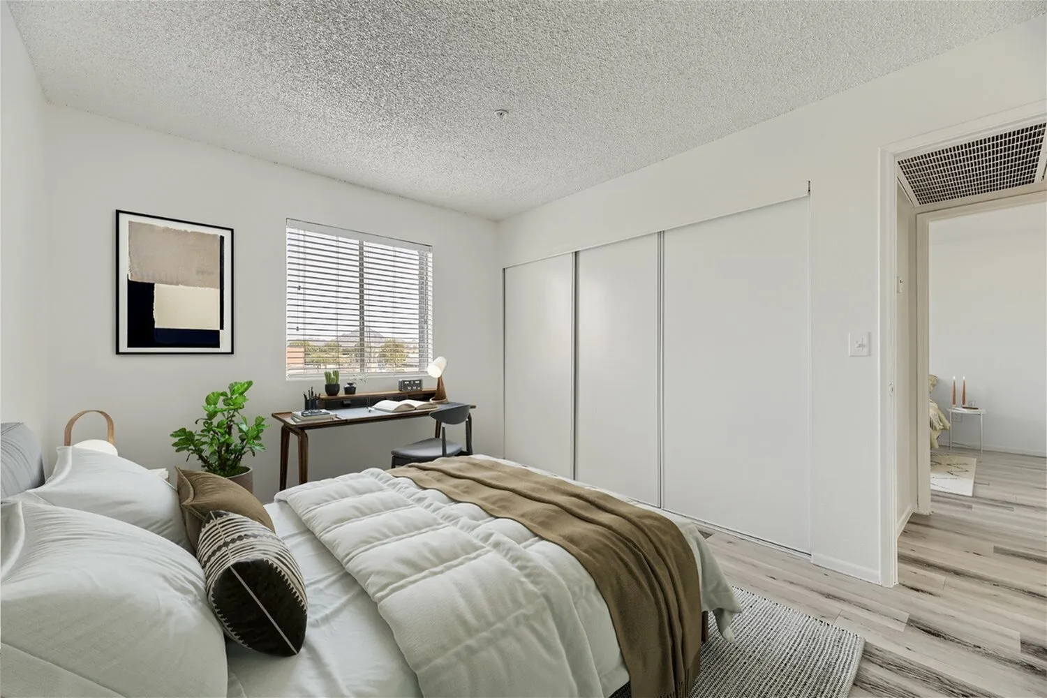 Primary bedroom, wood-style plank flooring, white bedding, sliding glass closet doors
