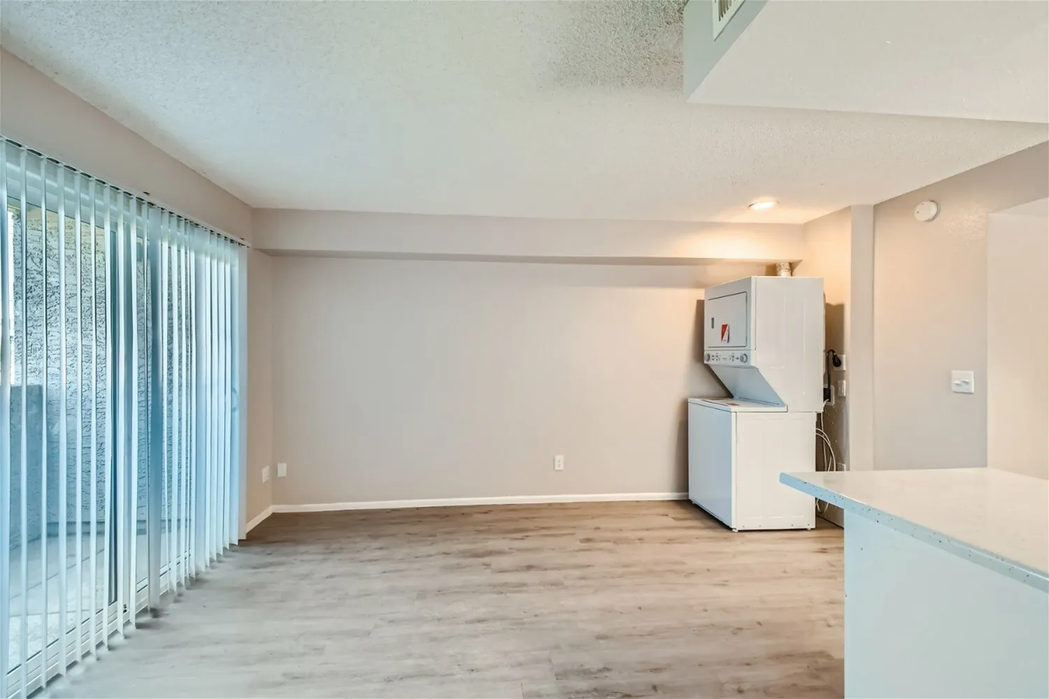Open concept space, wood-style plank flooring, vertical blinds, white appliances