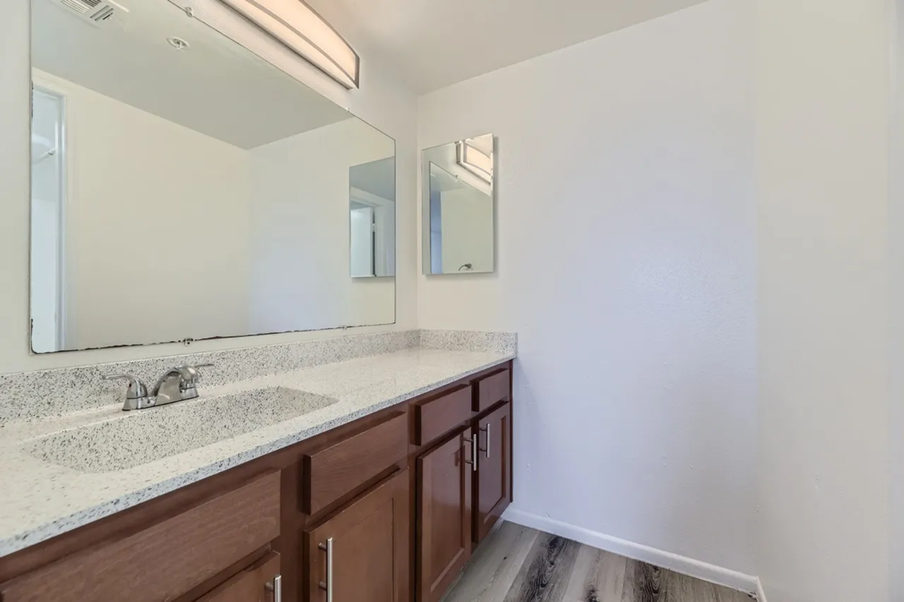 Bathroom, wood-style cabinetry, quartz countertop, chrome fixtures, large mirror