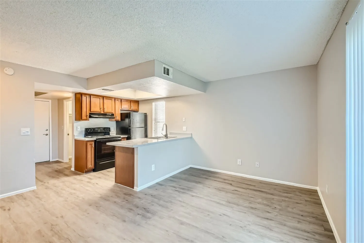 Kitchen and living room, wood cabinetry, stainless appliances, wood-style plank flooring, island counter