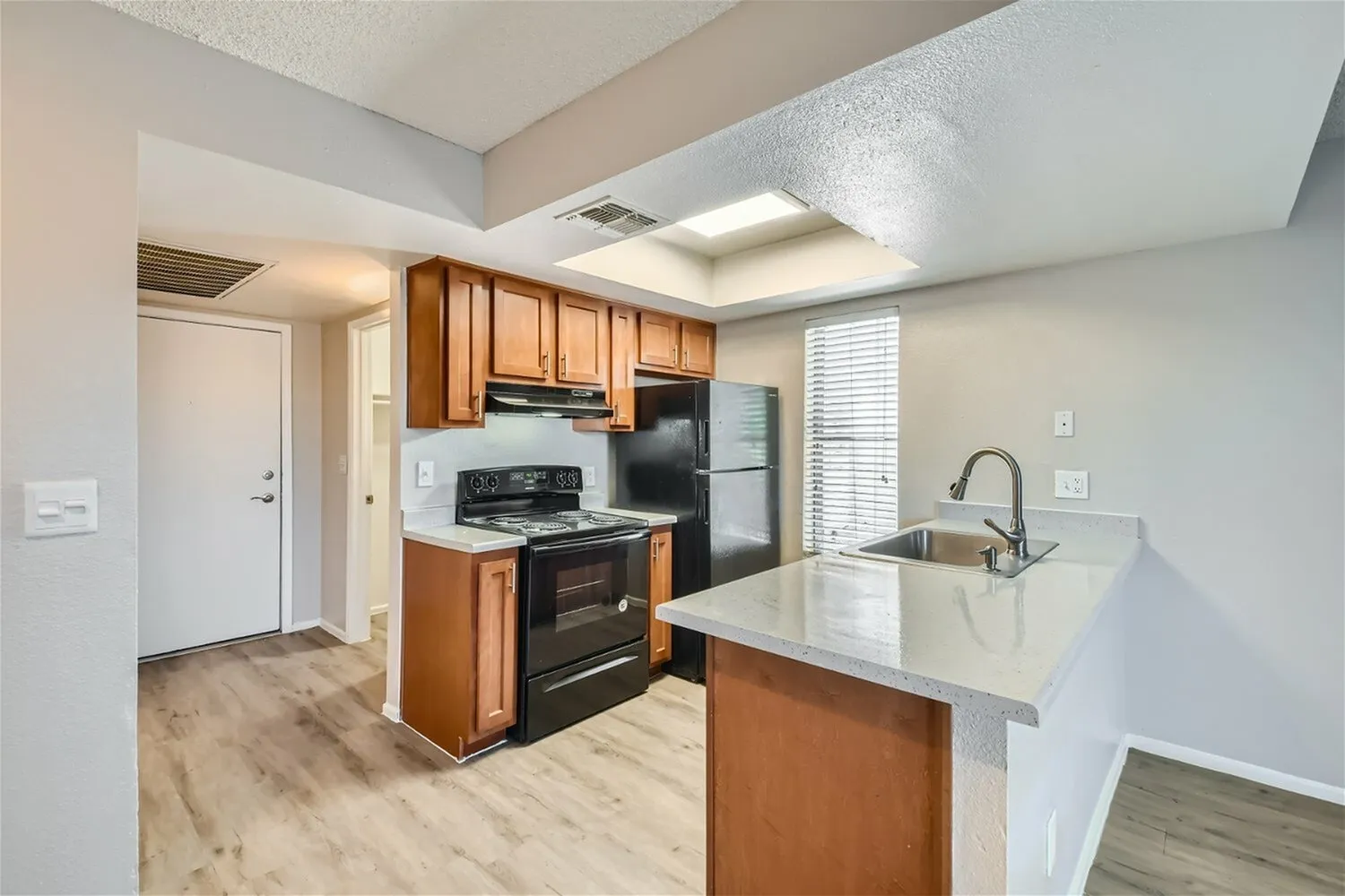 Kitchen, wood cabinetry, quartz countertops, stainless appliances, wood-style plank flooring