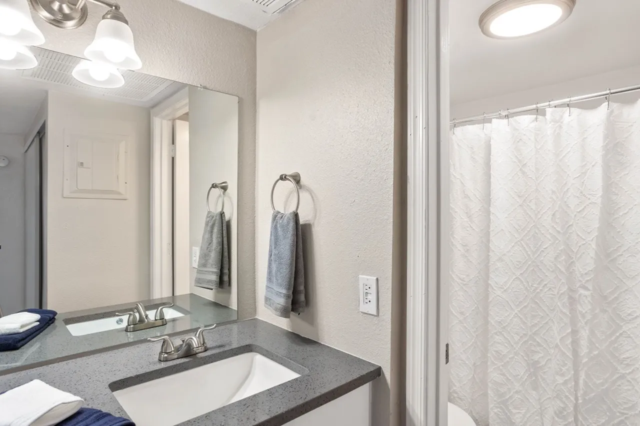 Bathroom, gray countertops, white undermount sink, large mirror, shower enclosure