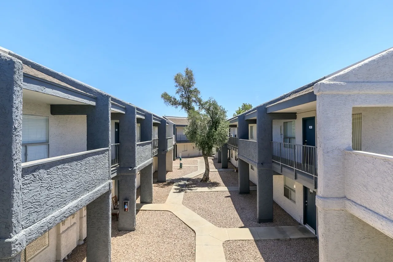 Courtyard pathway, modern low-rise apartments, desert landscaping, concrete walkway, clear sky