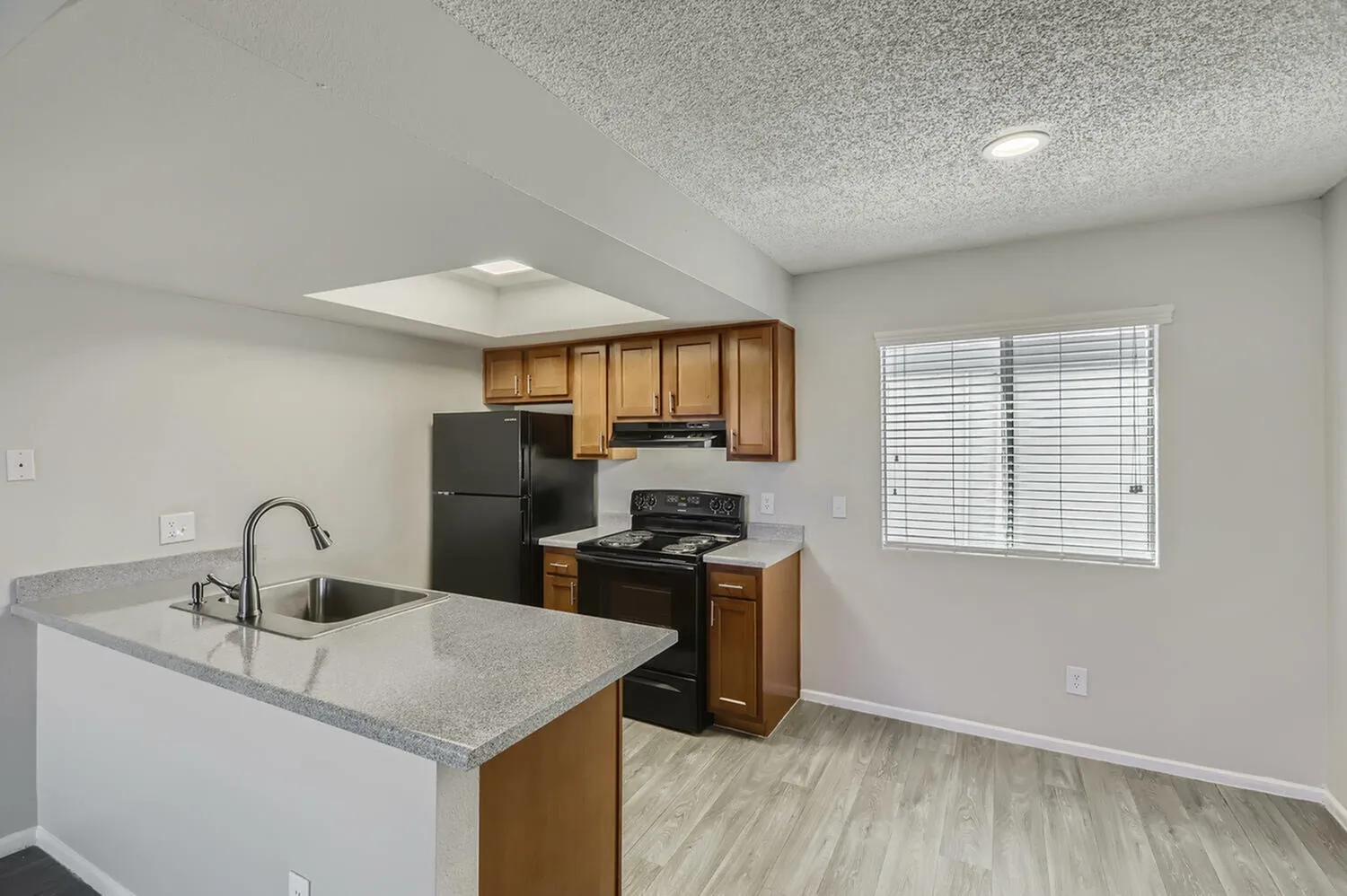 Kitchen, wood cabinetry, gray quartz countertops, black appliances, island with sink