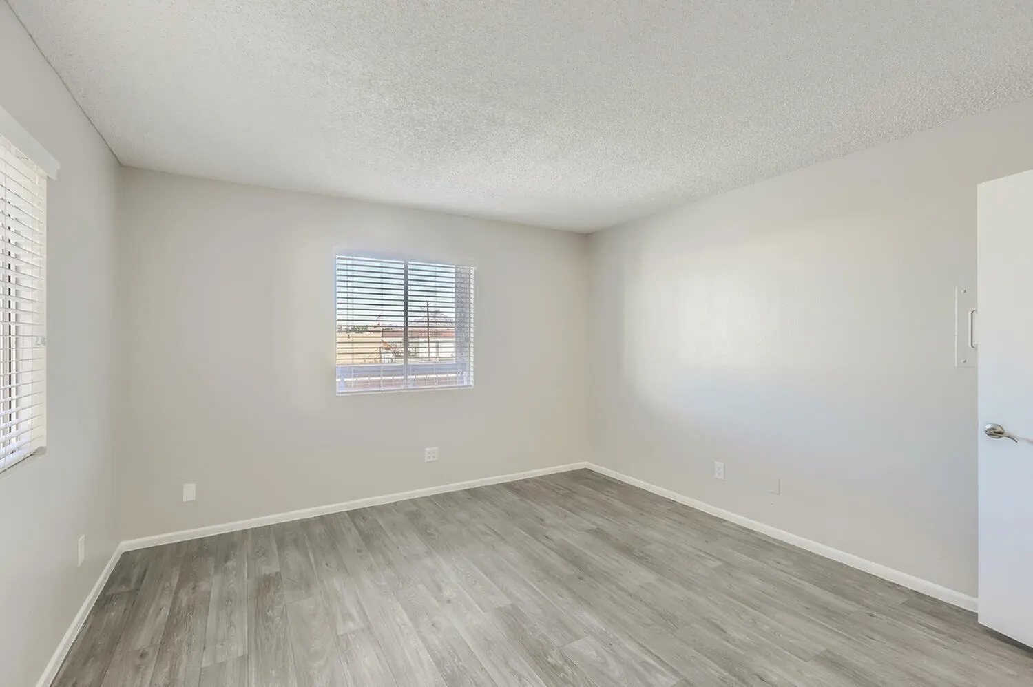 Bedroom, wood-style plank flooring, white walls, window with blinds, white door