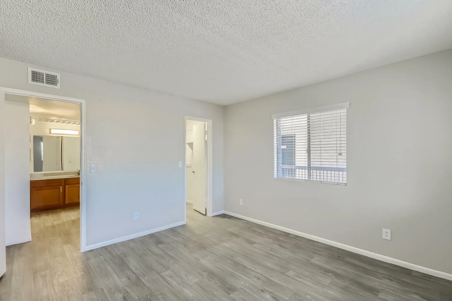 Primary bedroom, wood-style plank flooring, painted accent wall, window with shutters