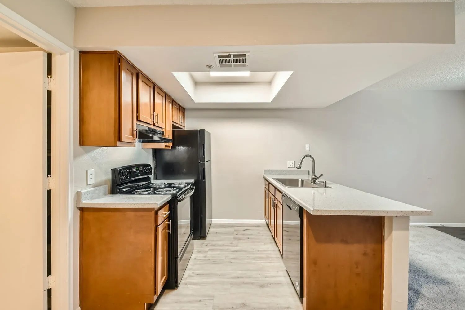Kitchen, wood cabinetry, white quartz countertops, black appliances, island with sink