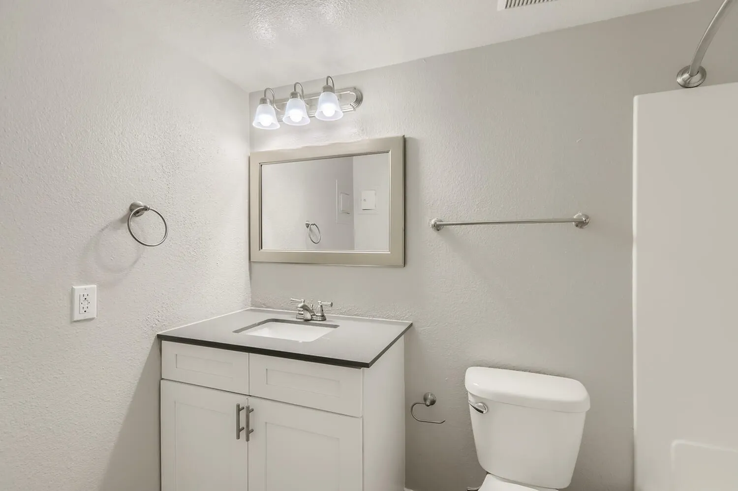 Bathroom, white cabinetry, framed mirror, chrome vanity fixtures, toilet