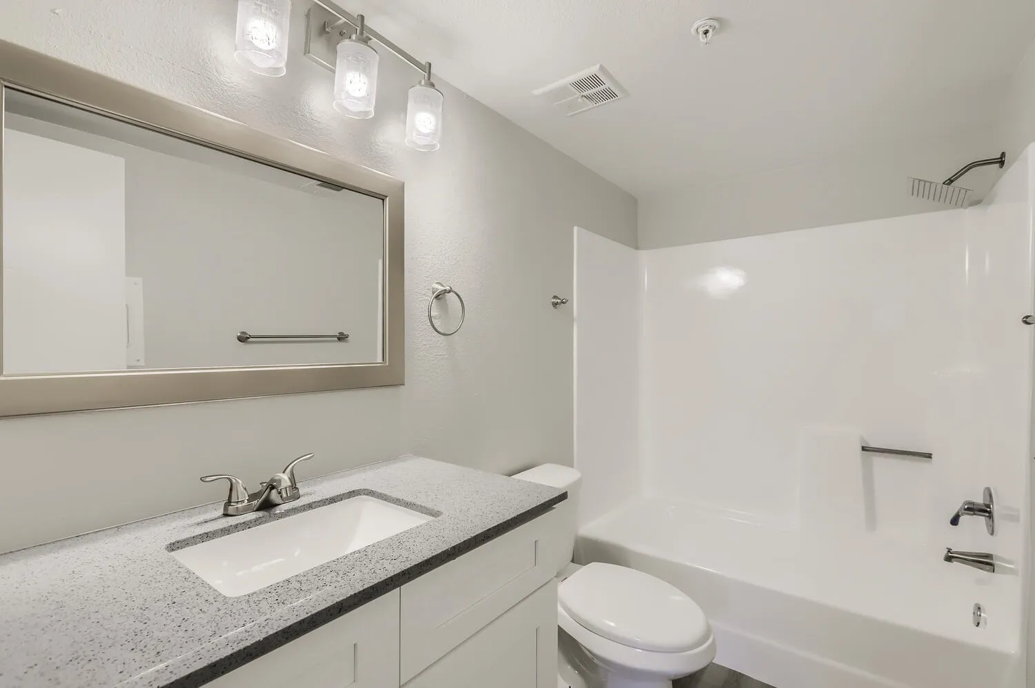 Bathroom, quartz countertops, white vanity cabinetry, white subway tile surround, framed mirror