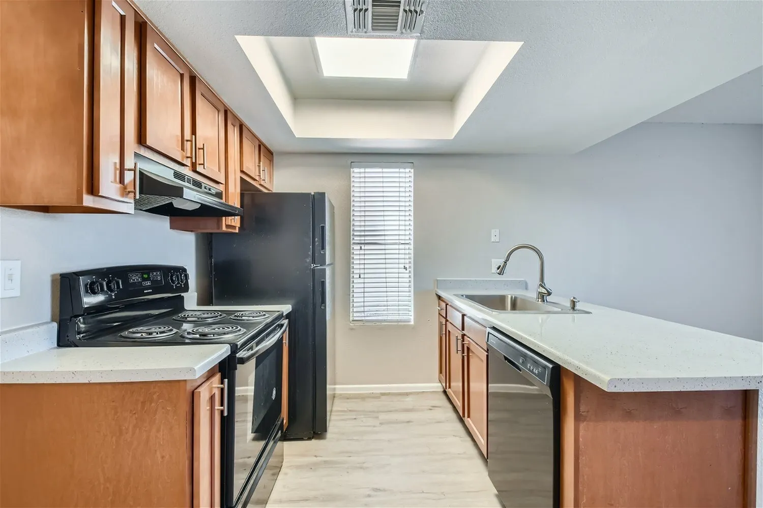 Kitchen, wood cabinetry, white quartz countertops, black stainless appliances, wood-style plank flooring
