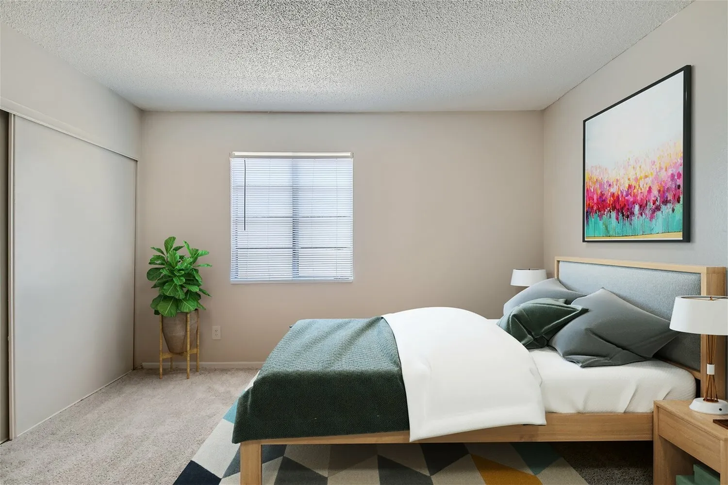 Primary bedroom, wood-style plank flooring, bed with layered bedding, nightstands, framed artwork, potted plant, window with blinds