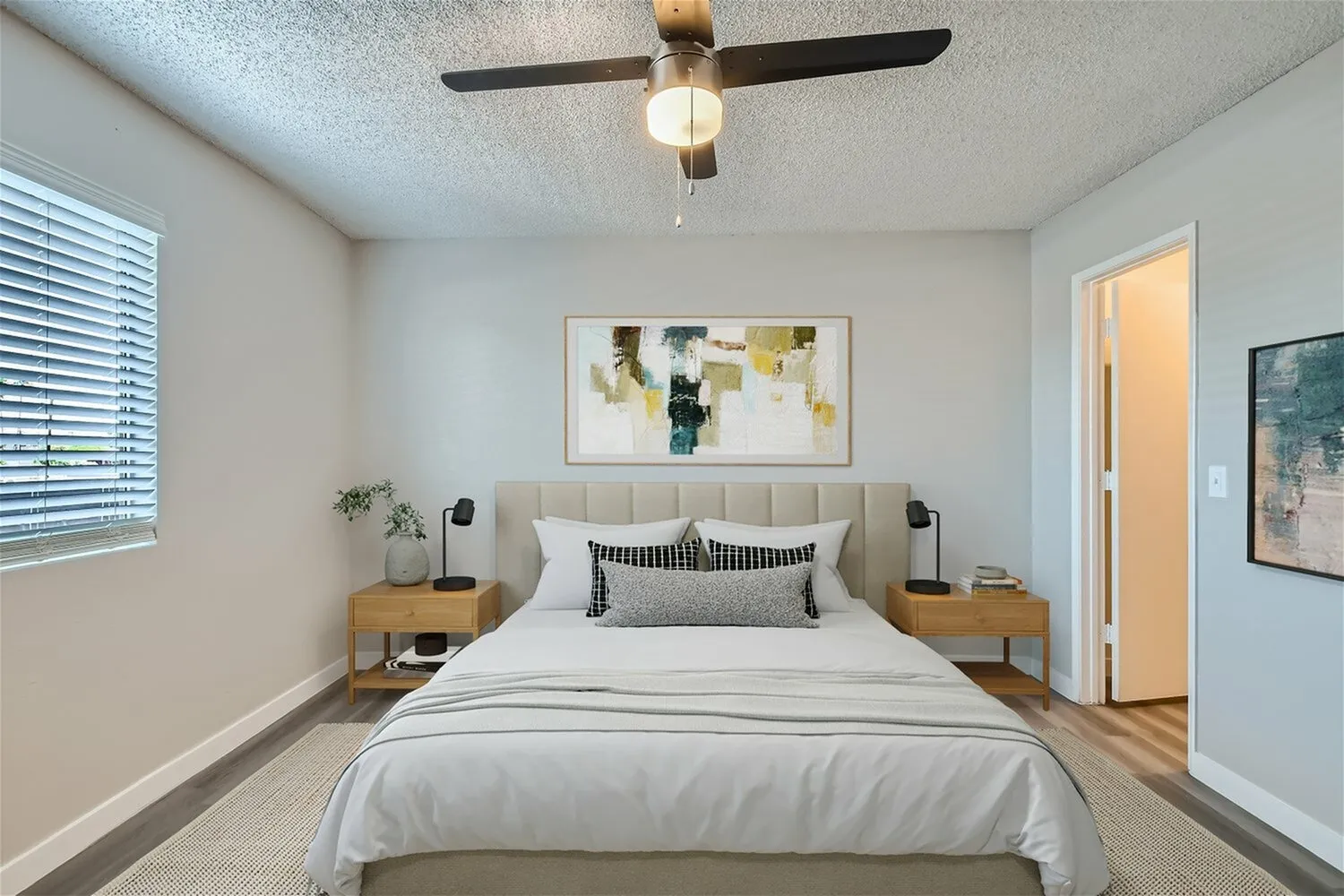 Primary bedroom, upholstered headboard, wood nightstands, ceiling fan, wood-style plank flooring