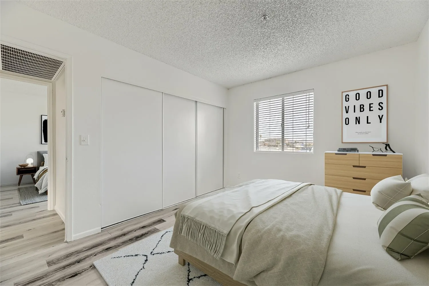 Primary bedroom, wood-style plank flooring, built-in closet with white sliding doors, wood dresser, window with shutters
