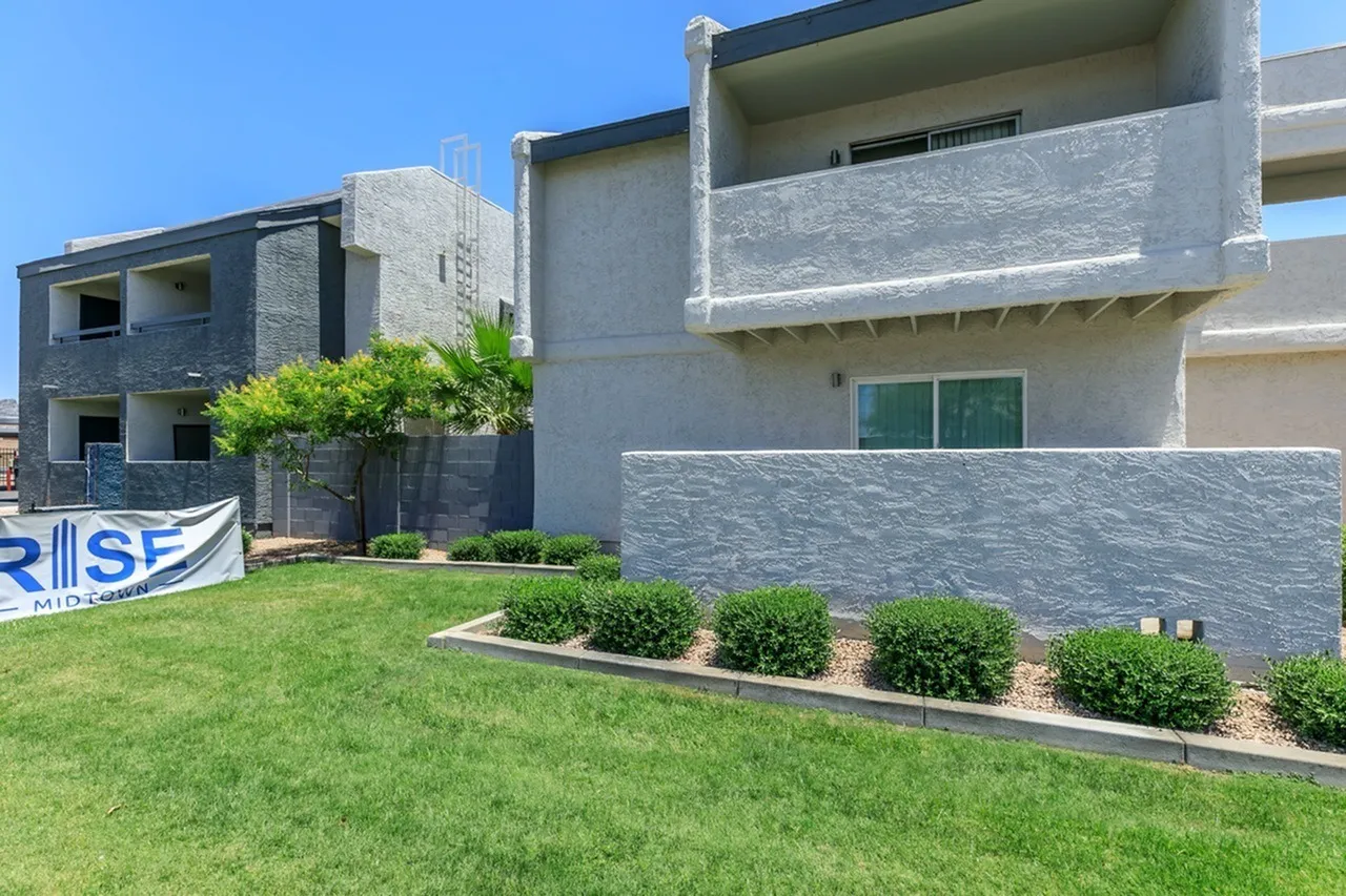 Modern residential building, concrete and stone facade, manicured lawn, landscaped shrub borders