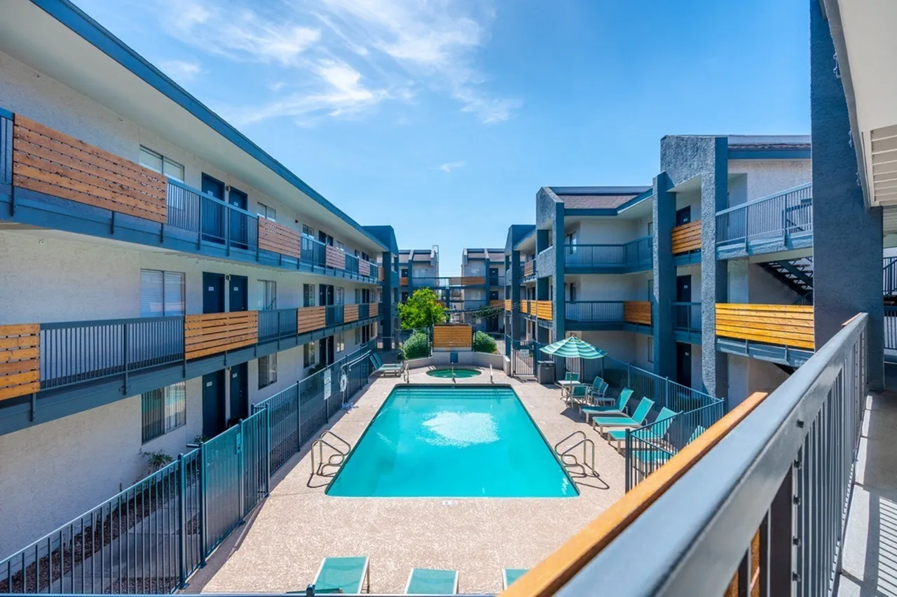 Courtyard pool area, blue water, lounge chairs, multi-story residential buildings