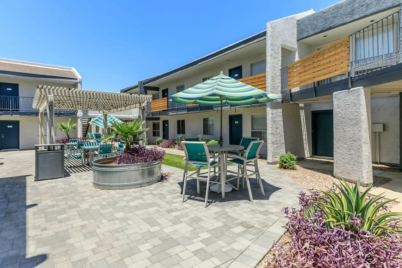Courtyard with paver flooring, striped umbrella, seating area, planters