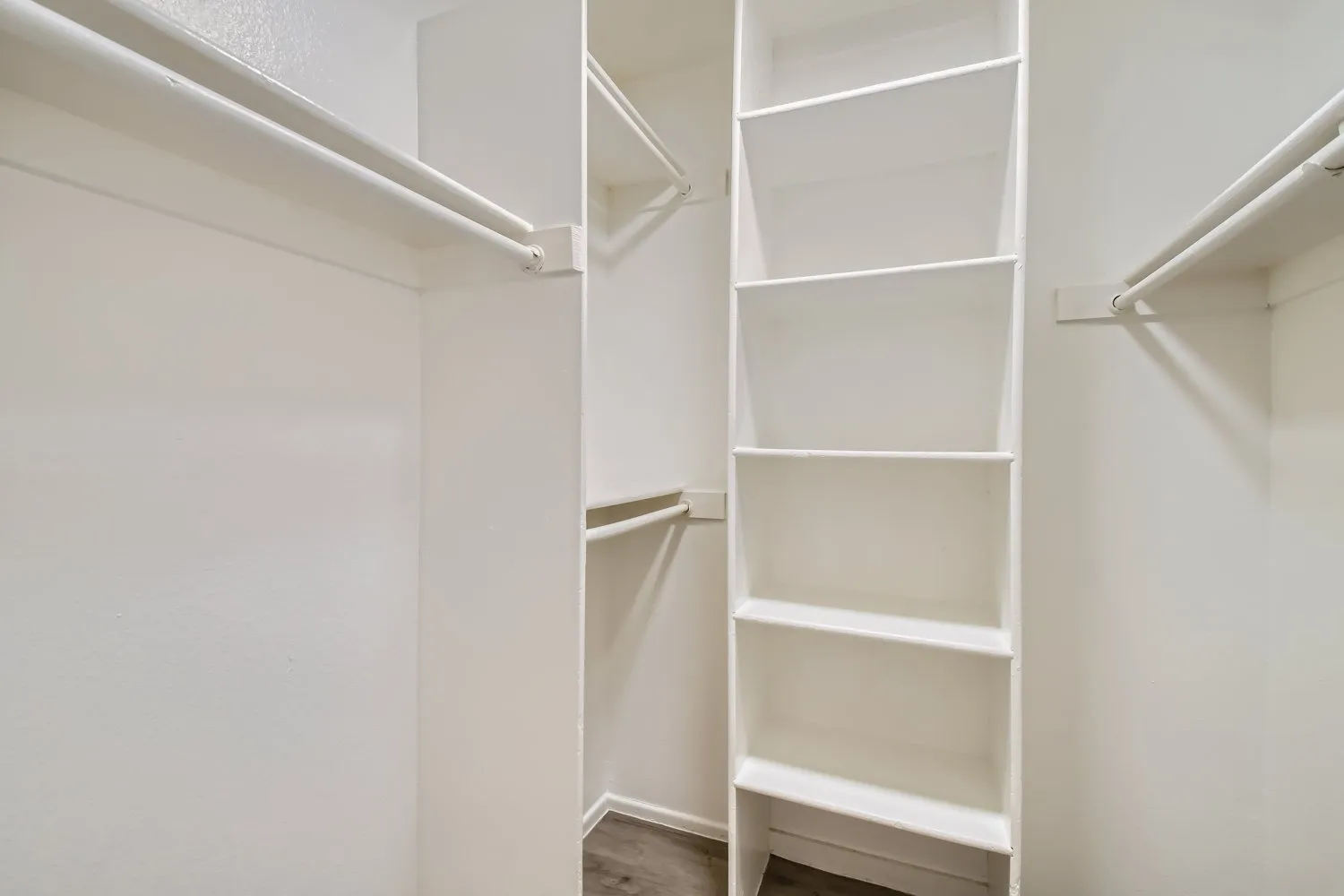 Walk-in closet, white shelving unit, clothing rods, recessed lighting