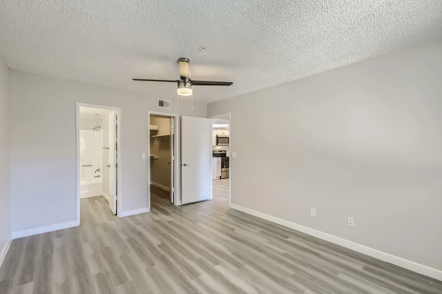 Primary bedroom, wood-style plank flooring, ceiling fan, walk-in closet, ensuite bathroom