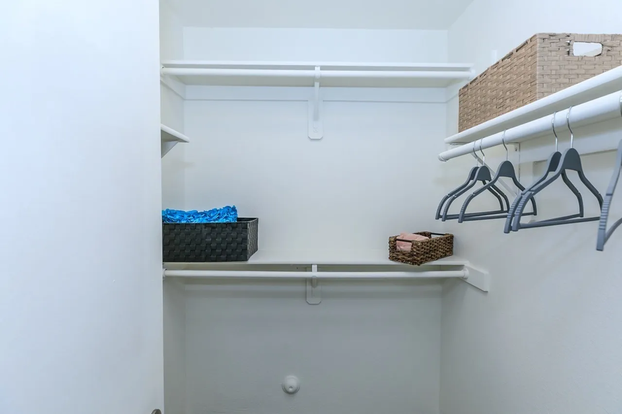 Closet, white shelving, metal hanging rod, storage baskets, dark hangers