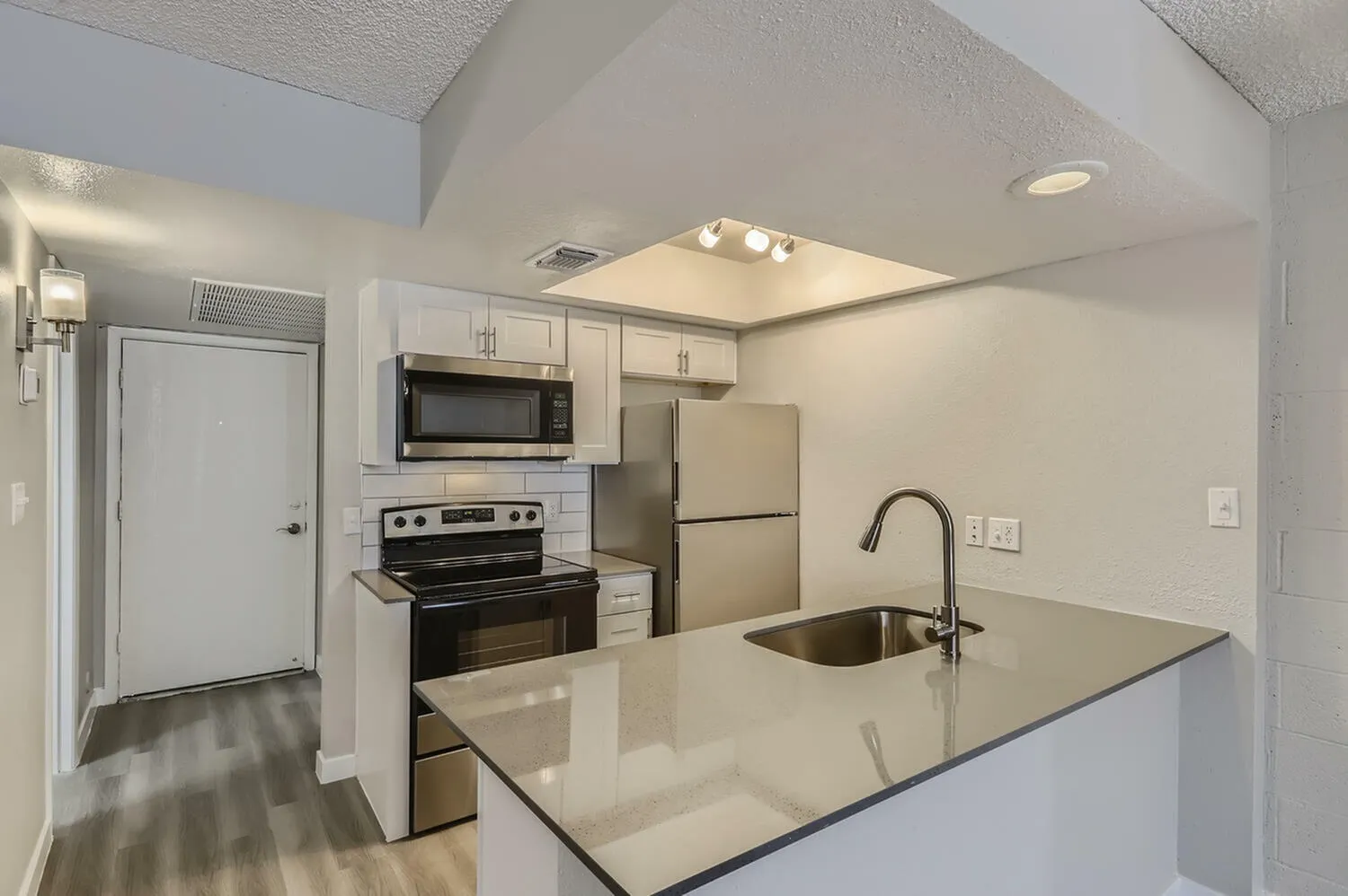 Kitchen, white shaker cabinetry, quartz countertops, black stainless appliances, wood-style plank flooring