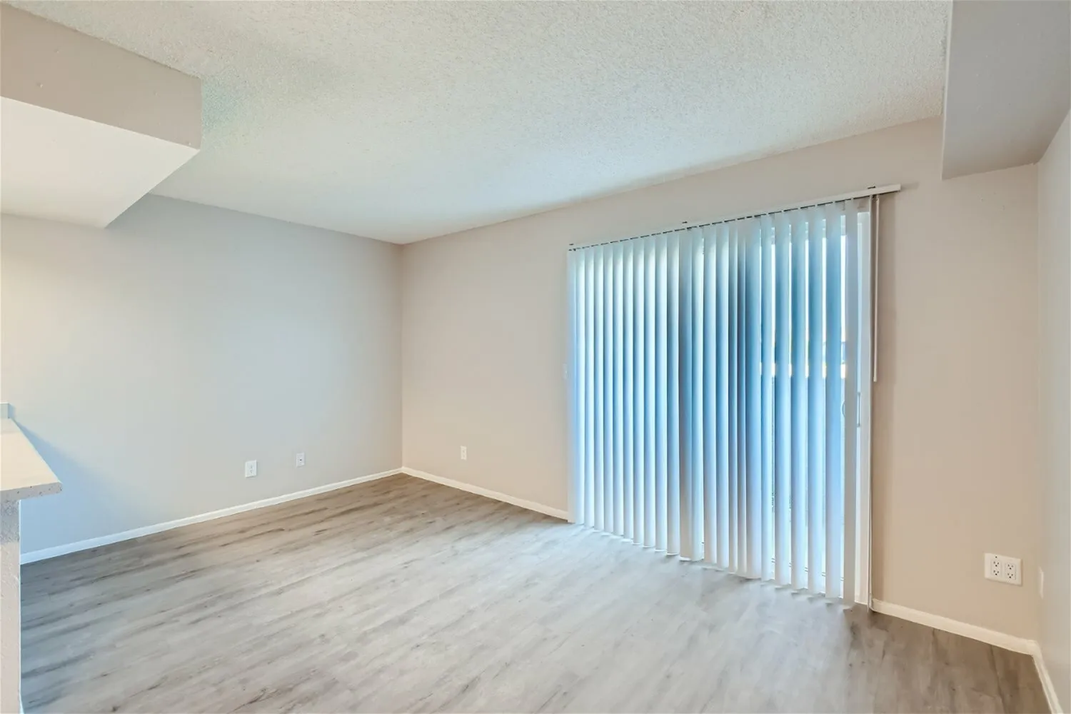 Living room, wood-style plank flooring, vertical blinds, white walls, recessed lighting