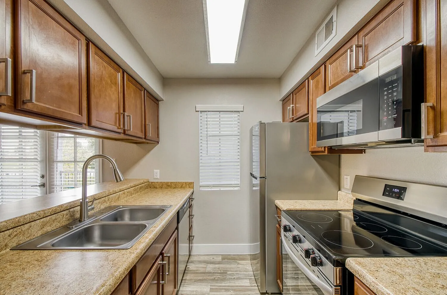 Kitchen, wood cabinetry, granite countertops, stainless appliances, wood-style plank flooring
