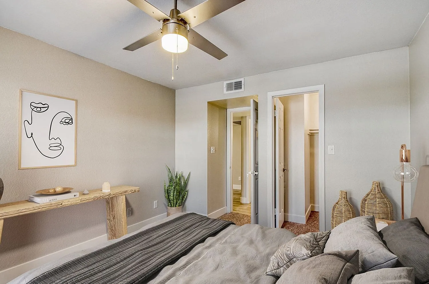 Primary bedroom, striped bedding, ceiling fan with brass finish, ensuite bathrooms, wood-style flooring, minimalist wall art