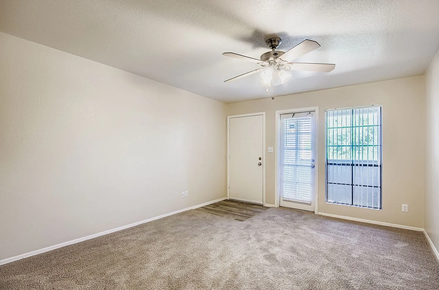 Living room, carpet flooring, ceiling fan, glass entry doors, shutters