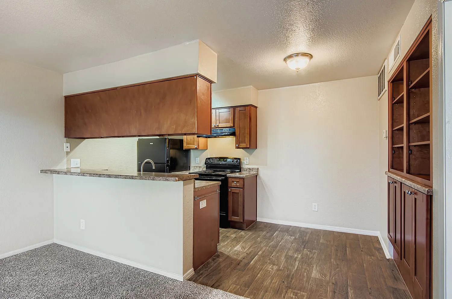 Kitchen, wood cabinetry, gray countertops, black range, wood-style plank flooring, built-in shelving
