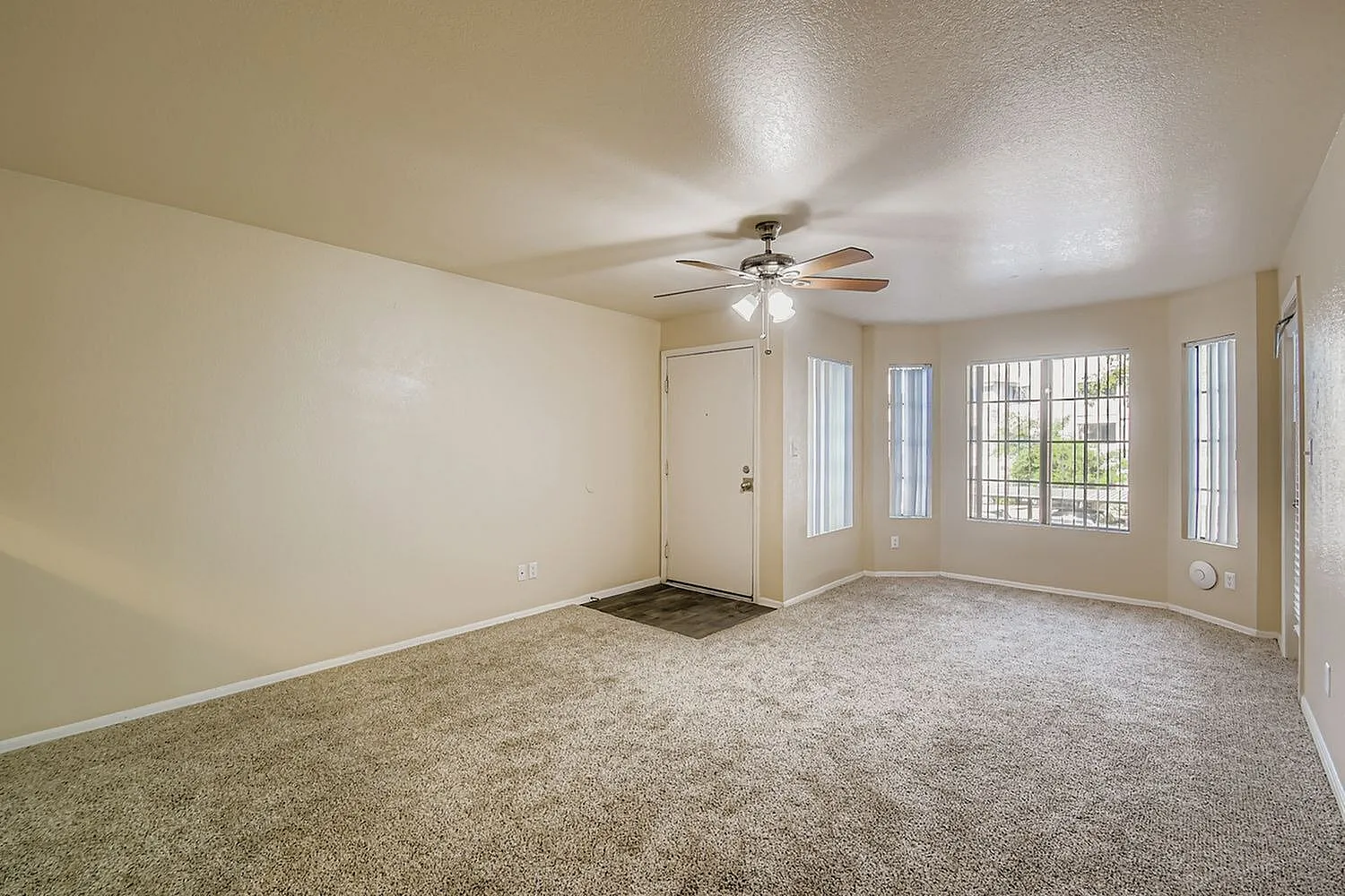 Primary bedroom, beige carpet flooring, ceiling fan, glass door and windows