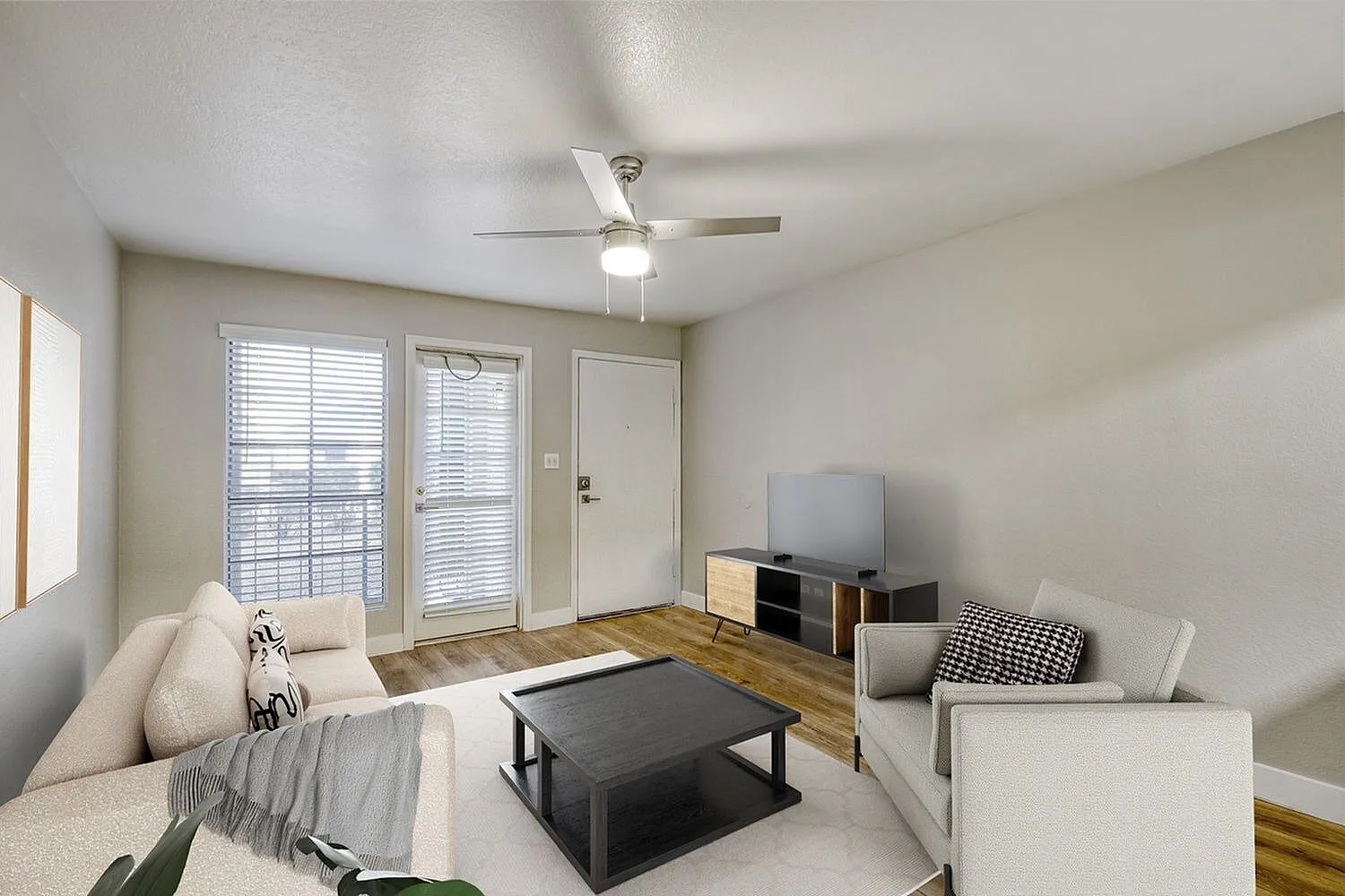Living room, wood-style plank flooring, ceiling fan, dark coffee table, entry doors with shutters