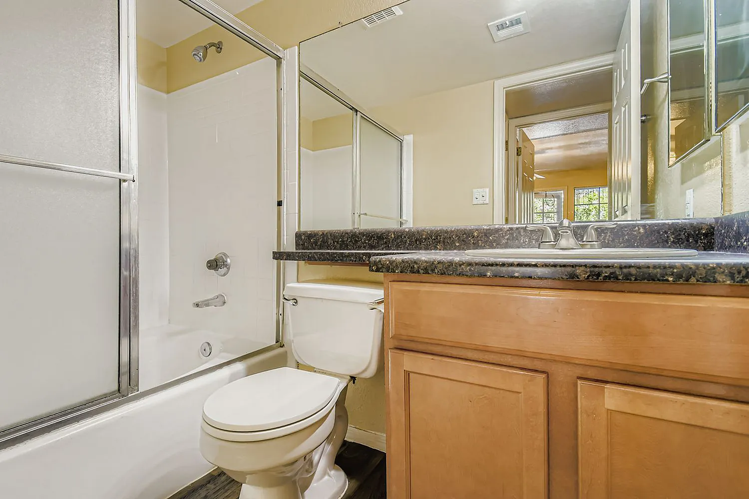 Bathroom, wood-style cabinetry, granite countertops, mirror, toilet