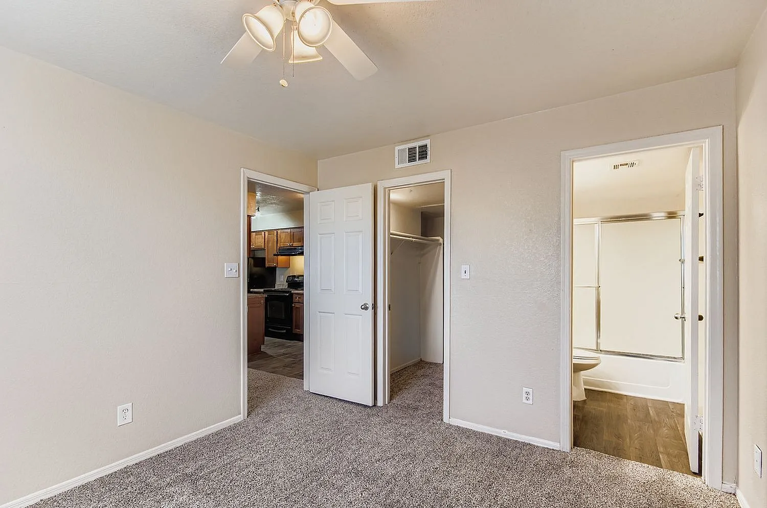 Primary bedroom, gray carpet flooring, ceiling fan, ensuite bathroom with vanity