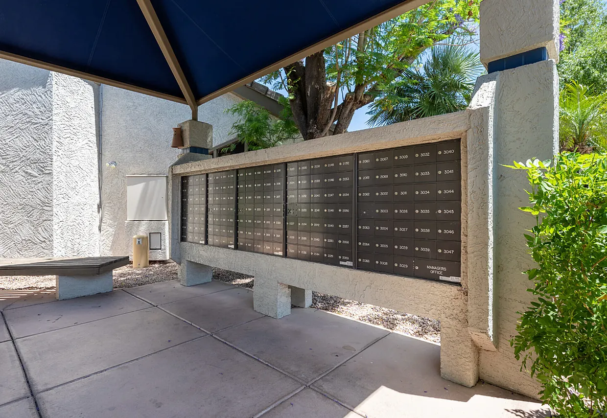 Covered patio area, wall-mounted mailboxes, concrete flooring, blue shade structure