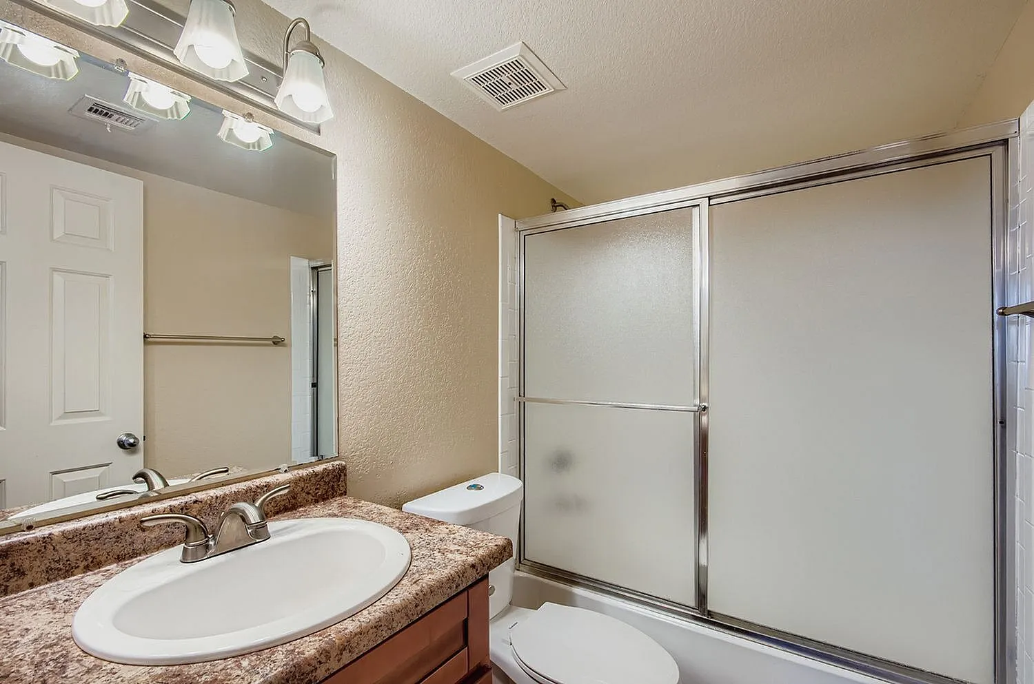 Primary bathroom, brown granite countertop, oval sink, frameless shower door
